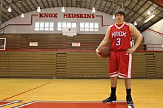 a young man standing on top of a basketball court holding a basketball in his hand