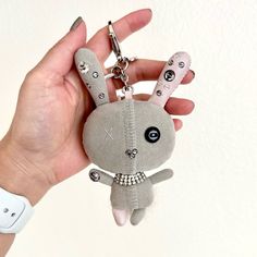 a hand holding a key chain with a stuffed animal on it