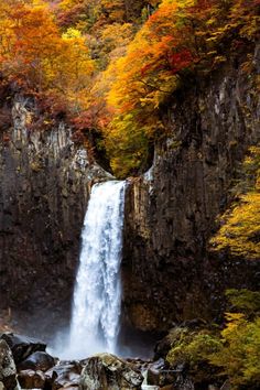 a waterfall with fall foliage surrounding it