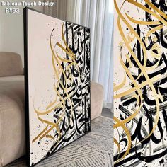 two paintings with gold and black designs on the wall next to a couch in a living room