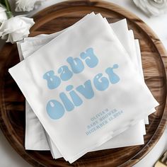 napkins that say baby deliverr on top of a wooden plate with white flowers