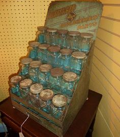 an old fashioned blue glass bottle display case on a wooden table next to a yellow wall