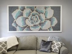 a living room with a gray couch and blue flower artwork on the wall above it