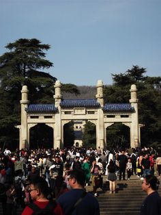 many people are walking up and down the stairs in front of an archway with blue roofing