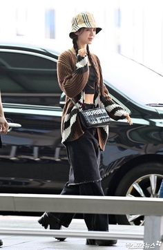 a woman walking across a street while wearing a hat and holding a cell phone to her ear