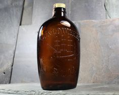 a brown glass bottle sitting on top of a stone slab