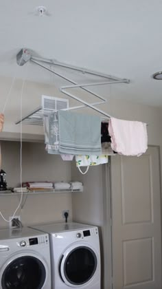 a woman is hanging clothes from a drying rack over a washer and dryer