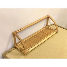 a rattan bench sitting on top of a wooden table next to a wall with a mirror