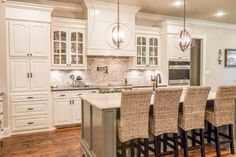 a large kitchen with white cabinets and wooden floors