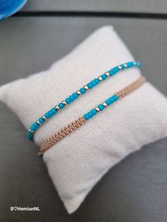 two beaded bracelets sitting on top of a pillow