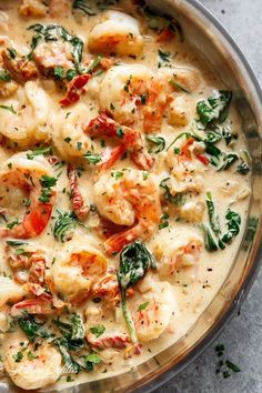 a pan filled with shrimp and spinach covered in sauce on top of a table