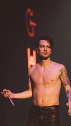 a shirtless man holding a pair of scissors in his right hand while standing on stage