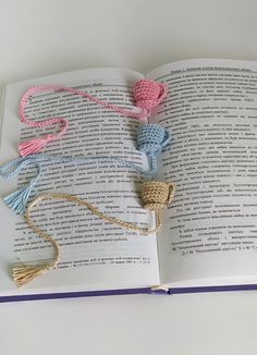 an open book with crocheted tassels on it