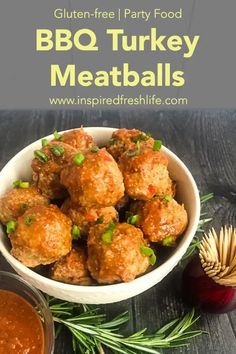 meatballs in a white bowl with sauce and herbs on the side next to it