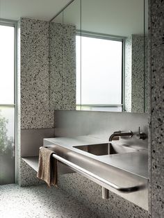 a bathroom sink sitting under a mirror next to a window with a towel hanging on it