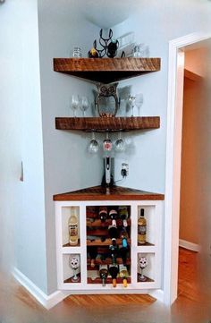 a wine rack in the corner of a room filled with bottles and glasses on top of shelves