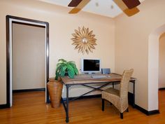 a room with a desk, chair and ceiling fan