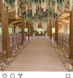 an indoor wedding venue with white flowers and greenery on the ceiling, along with candles