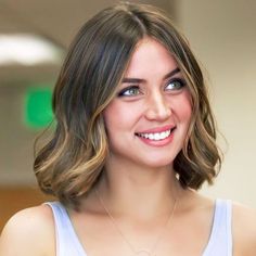 a close up of a person wearing a tank top and smiling at the camera with a necklace on her neck