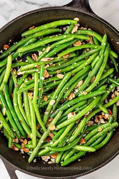 green beans with almonds in a cast iron skillet on a marble countertop