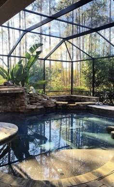 an indoor swimming pool in the middle of a patio area with glass walls and stone steps