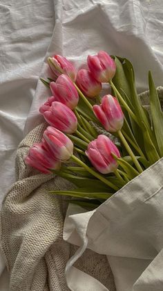 a bunch of pink tulips sitting on top of a white cloth