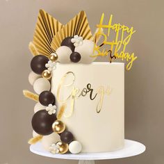 a birthday cake decorated with gold, white and black decorations on top of a table