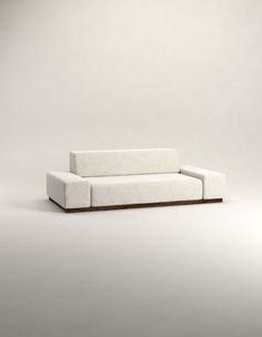 a white couch sitting on top of a wooden frame in front of a gray wall