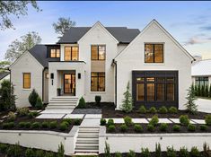 a white house with black windows and steps leading up to the front door is shown