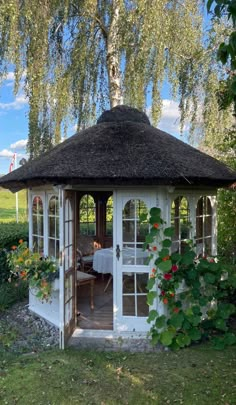 a white gazebo sitting in the middle of a lush green field