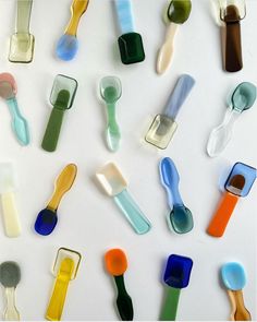 many different colored glass spoons on a white surface