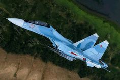 an aerial view of a fighter jet flying in the sky over land and grass area