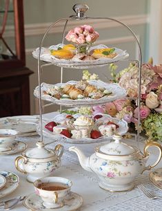 an assortment of tea and pastries on a table with pink flowers in the background