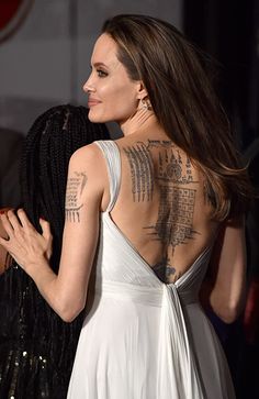 the back of a woman's dress with tattoos on her upper and lower body