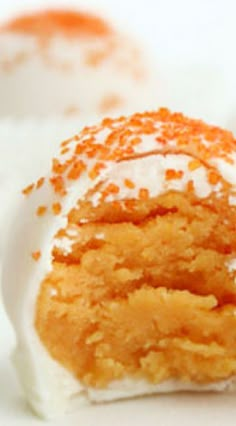 an orange cake with white frosting and sprinkles on it's side