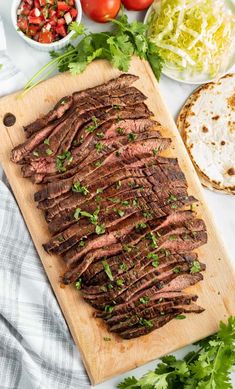 sliced flank steak on a cutting board with salad and pita bread