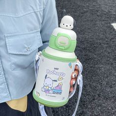 a person holding a green and white baby bottle in their left hand while wearing a blue shirt