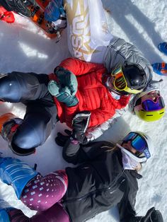 several people standing in the snow with skis and goggles on their feet, looking down at them