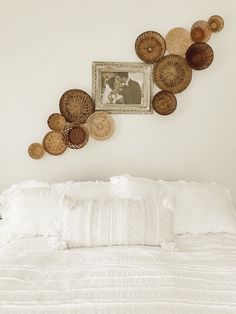 a white bed topped with lots of pillows and pictures on the wall next to it