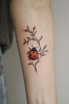 a ladybug tattoo on the arm with leaves and flowers around it's perimeter