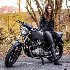 a woman sitting on top of a black motorcycle