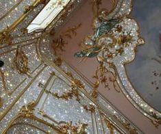 the ceiling is decorated with gold and white glitters in this ornately designed room