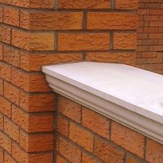 the corner of a brick building with a white window sill on it's side