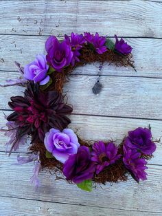 purple flowers are arranged in the shape of a wreath on a white wooden background,