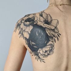 the back of a woman's shoulder with flowers and an apple tattoo on it