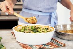 a person in an apron spooning food out of a dish with broccoli