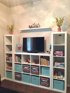 there is a television on top of the bookshelves in this room with blue bins