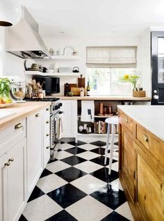 a kitchen with black and white checkered flooring on the walls, an island in the middle