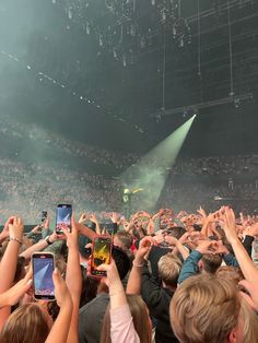 a crowd of people at a concert with their cell phones in the air and one person on stage