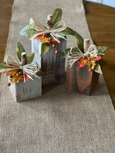 three small wooden boxes with bows on them sitting on top of a cloth covered table